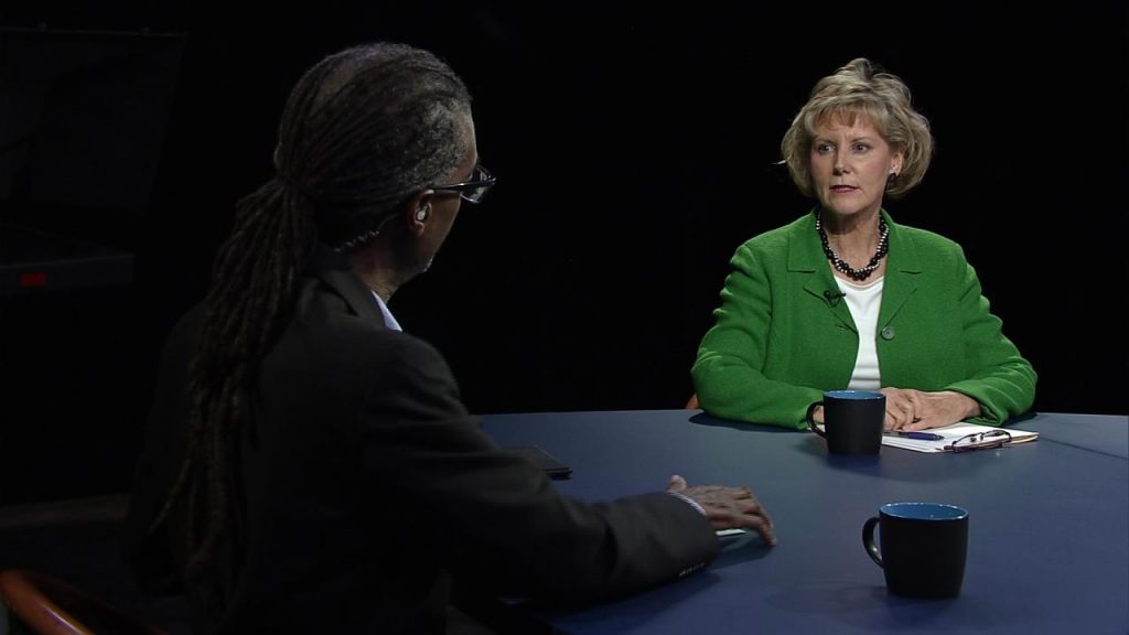 Two women sitting at a table talking to each other.