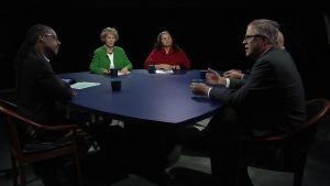 Four people sitting around a table in a dark room.
