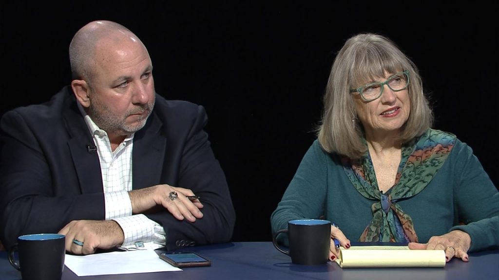 A man and woman sitting at a table with a cup of coffee.