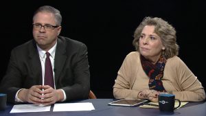 A man and woman sitting at a table with a cup of coffee.