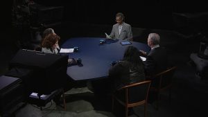 A group of people sitting around a table in a dark room.