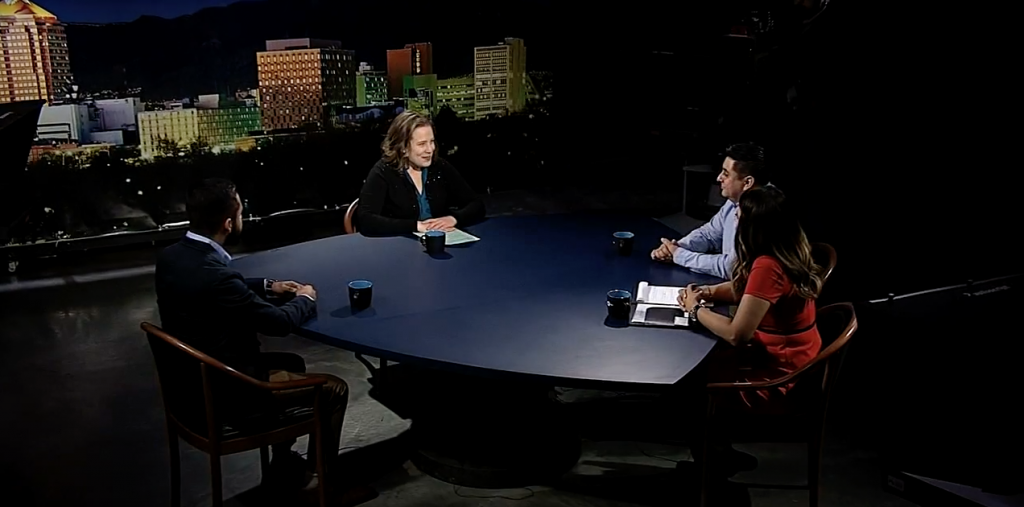 A group of people sitting around a table in front of a city.