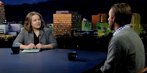 A man and woman sitting at a table in front of a city.