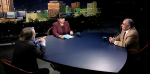 Three people sitting at a table in front of a city.