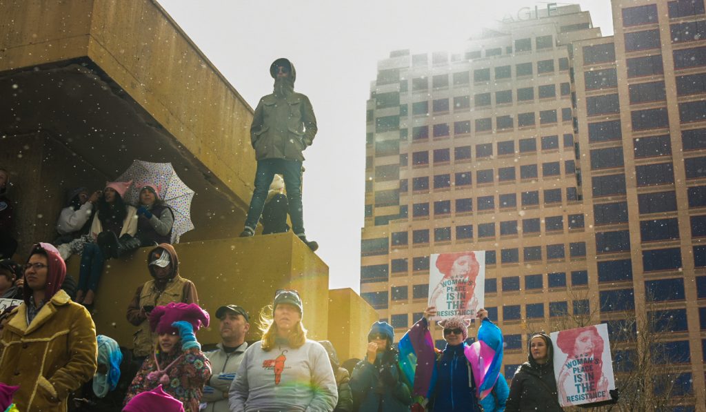 Snow falls on rally goers standing on the Civic Plaza fountain during the ABQ Women’s Rally, Saturday, Jan. 21st, 2017, in NM. The rally in Albuquerque was a single gathering held in concert with hundreds of rallies and marches spread across the country and around the world. The sister rally in Civic Plaza was “to show solidarity across the nation and at home,” according to social media accounts affiliated with the rally. (Kevin Maestas / @ DailyLobo) 