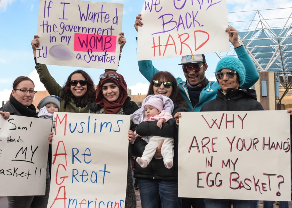 From left to right, Erika Eddy, Felix Baca, Keelin, Sabrin, Rebekah, Scarlett Baca, Seth, and Adrienne of the Hindi family hold signs in response to the inauguration of Donald Trump and his policies, Saturday, Jan. 21st, 2017, in Albuquerque, NM. The rally in Albuquerque was a single gathering held in concert with hundreds of rallies and marches spread across the country and around the world. The sister rally in Civic Plaza was “to show solidarity across the nation and at home,” according to social media accounts affiliated with the rally. (Kevin Maestas / @ DailyLobo) 