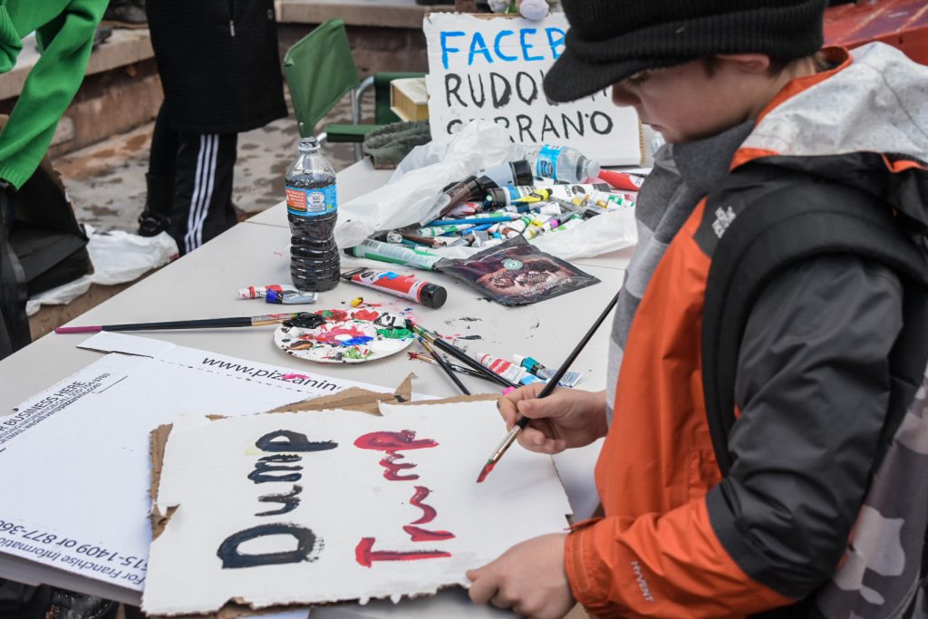 Aaron Edwards creates a sign near the Civic Plaza fountain, Saturday, Jan. 21st, 2017, in Albuquerque, NM. The rally in Albuquerque was a single gathering held in concert with hundreds of rallies and marches spread across the country and around the world. The sister rally in Civic Plaza was “to show solidarity across the nation and at home,” according to social media accounts affiliated with the rally. (Kevin Maestas / @ DailyLobo) 