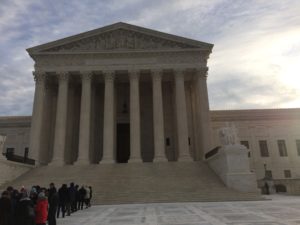 A group of people standing in front of the supreme court building.