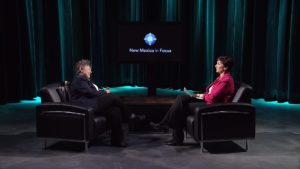 Two women sitting in chairs in front of a green screen.