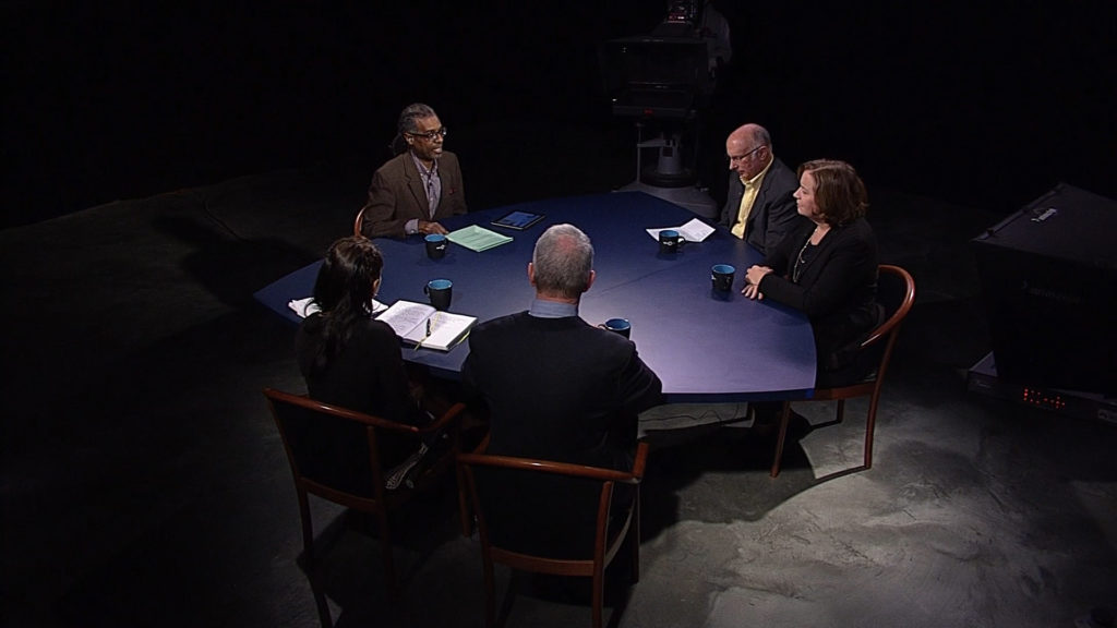 Four people sitting around a table in a dark room.