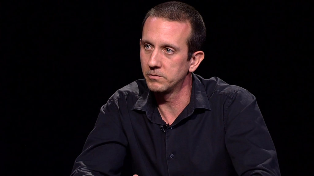 A man in a black shirt sitting at a table.