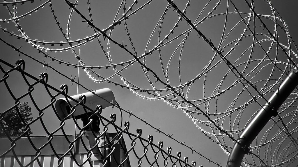 A black and white photo of a barbed wire fence.