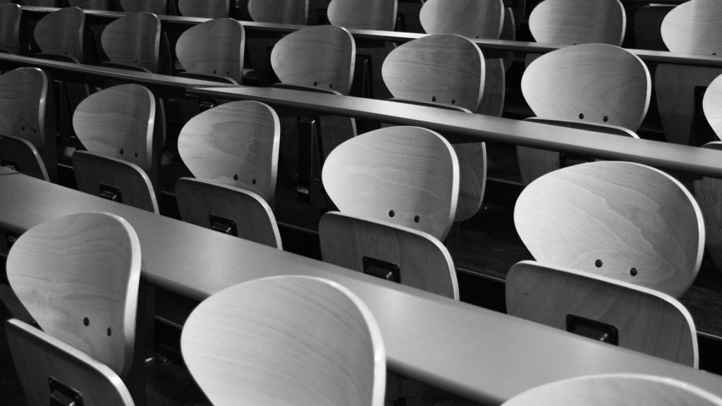 A black and white photo of rows of chairs in a lecture hall.
