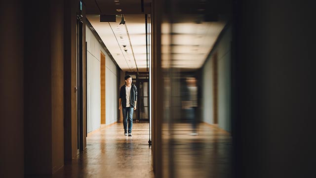 A woman walking down a hallway in a business office.