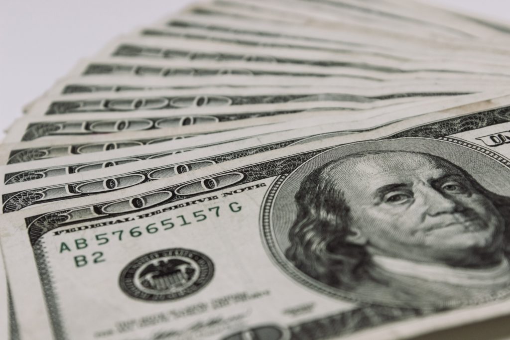 A stack of one hundred dollar bills on a white background.