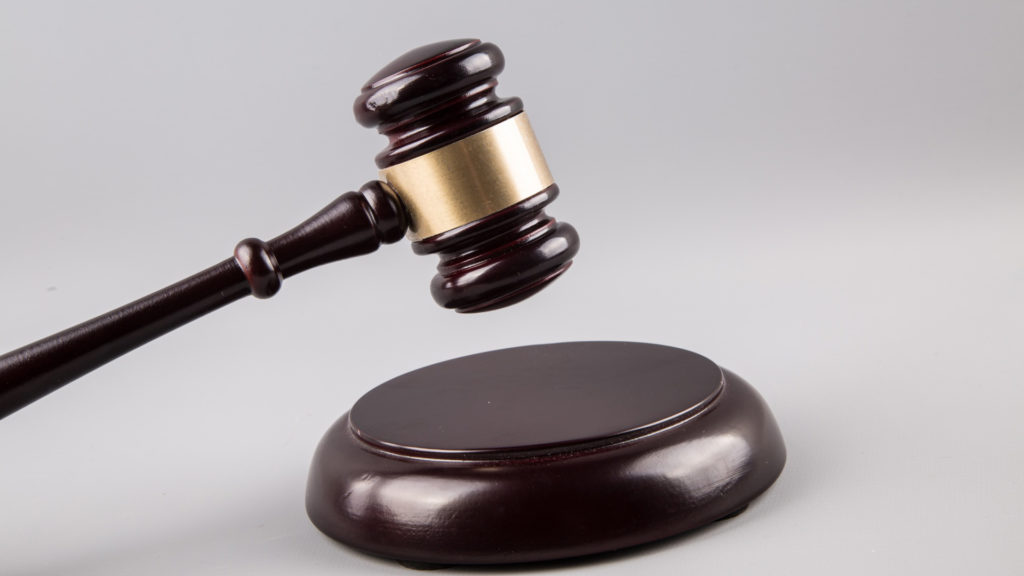 A wooden gavel on top of a gray background.