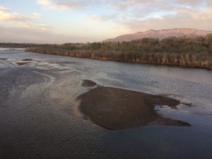 An aerial view of a river with mountains in the background.