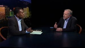 Two men sitting at a table talking to each other.