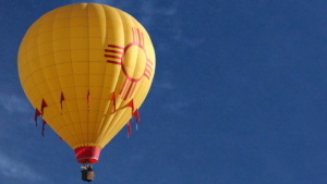 A hot air balloon depicting the New Mexico flag flies into the air.