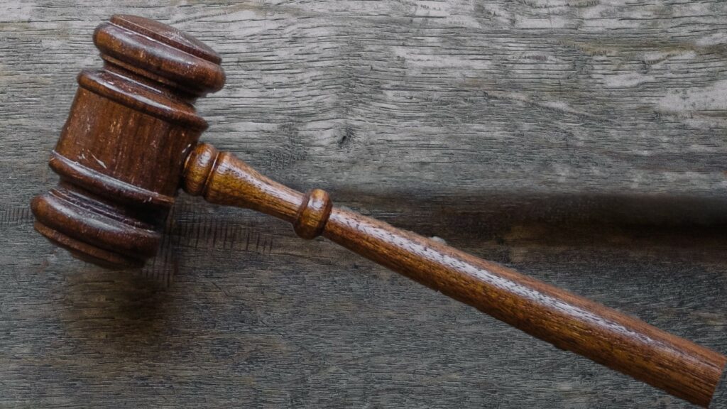 A wooden gavel lying on a grey wooden table.