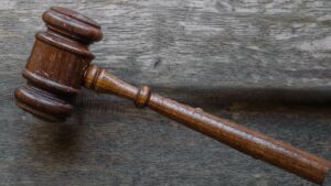 A wooden gavel lying on a grey wooden table.