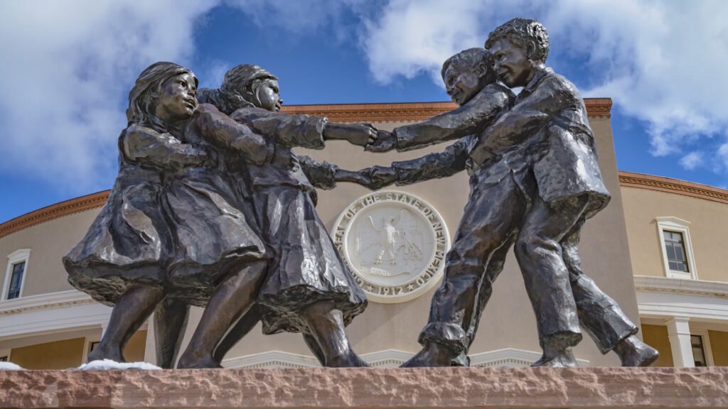 Close-up of a sculpture in front of the Santa Fe Roundhouse depicting two groups of children tugging on each other.