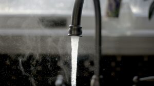 Close-up of a faucet gushing water, with some water spraying back.
