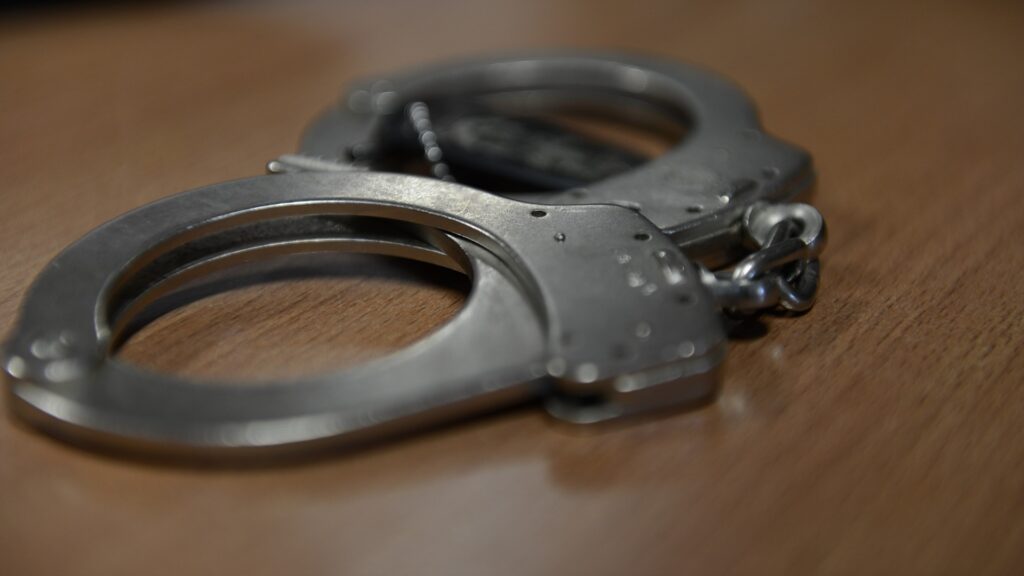 Close-up of handcuffs sitting on a wooden table.