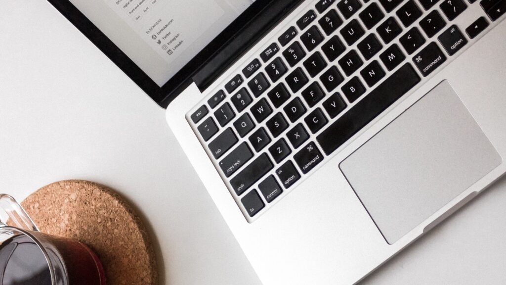 A laptop and cup of coffee on a surface.