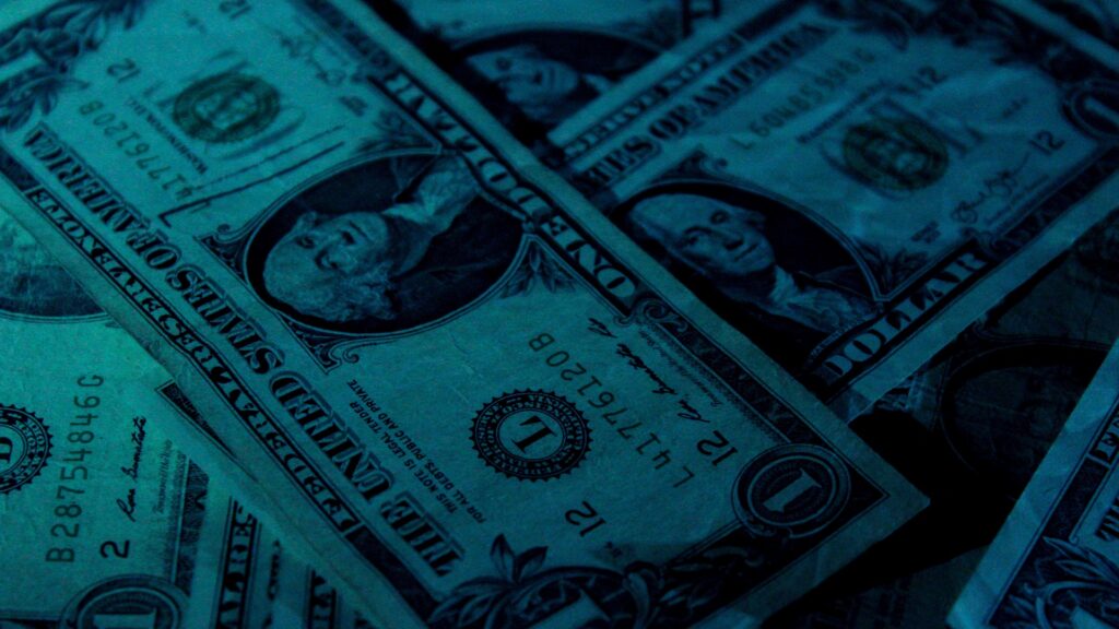 Close-up of a pile of $1 dollar bills, tinted blue-green.