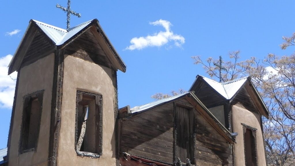 A small building with two crosses on top of it during mid-day.