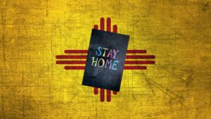 Composite of a sign reading "STAY HOME" in colorful text, with the New Mexico flag behind it.