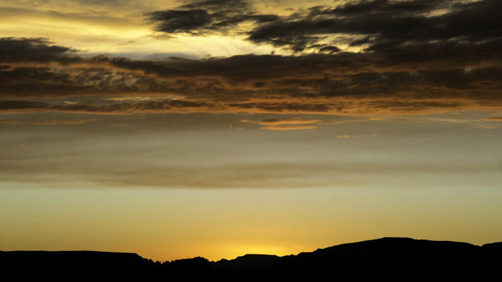 A very yellow sunset, with the sun eclipsed by a mountain range.
