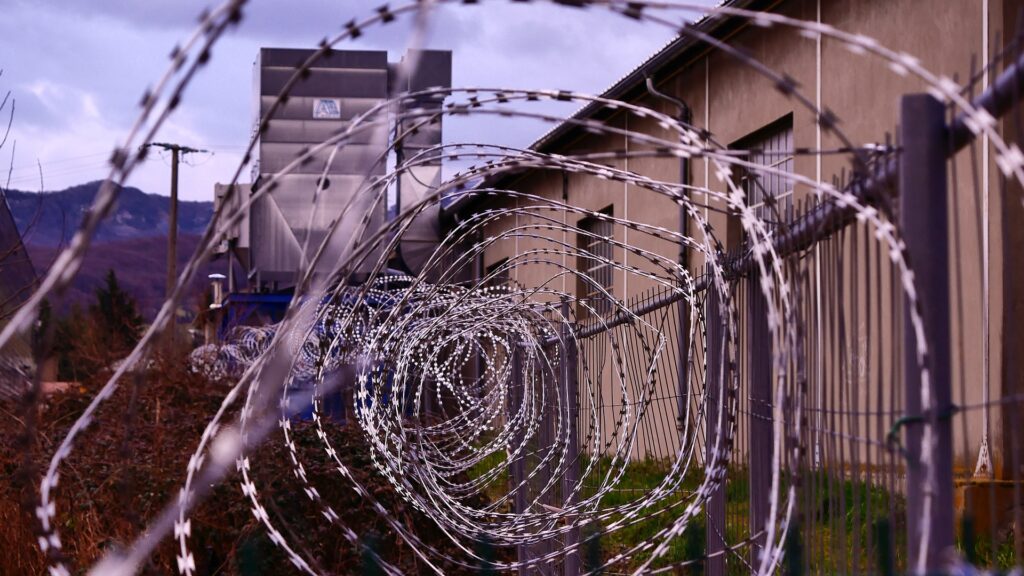Close-up of hoops of barbed wire in front of a jail.