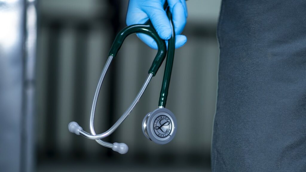 Close-up of a gloved hand holding a stethoscope.