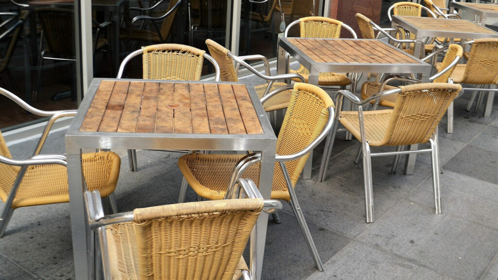 A cluster of wood-metal tables on a city street.