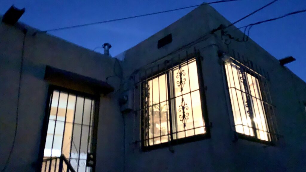 A window with a gate in front of it, in front of a dark blue sky.