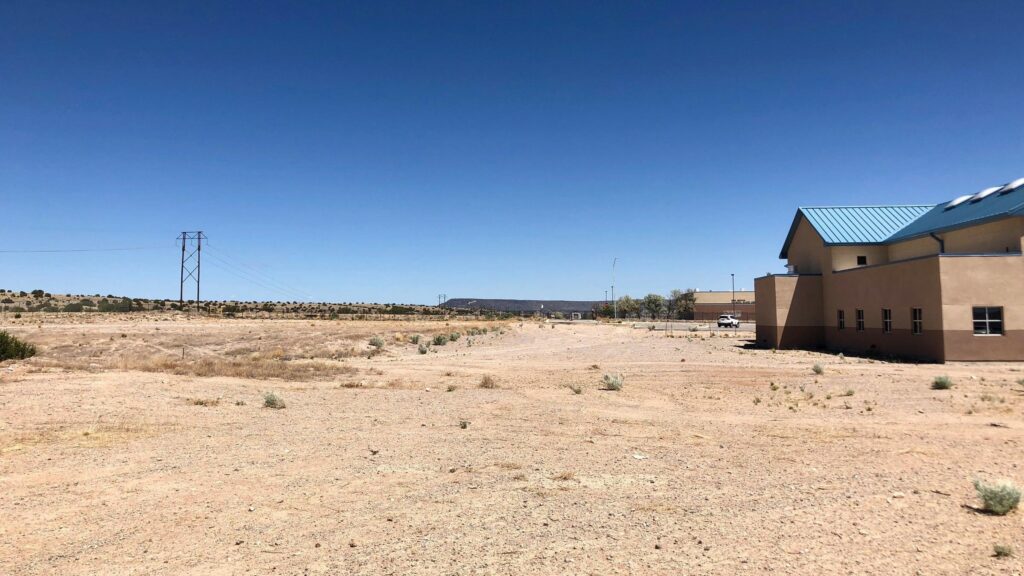 Barren desert land, with a few buildings and power lines accompanying it.