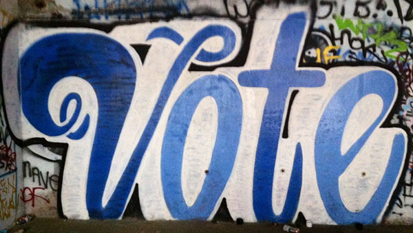 Graffiti in script font reading "Vote".