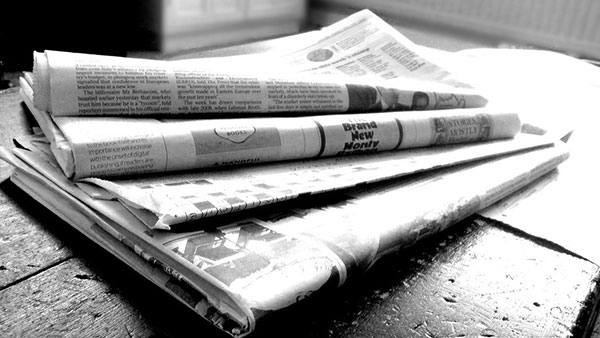 A stack of newspapers on a stoop.