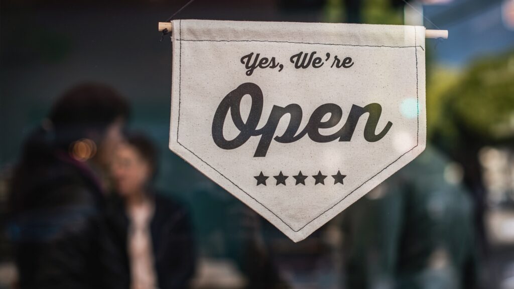 A storefront with a cloth sign reading "Yes, We're Open".