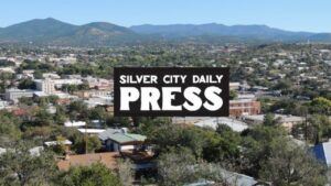 Composite of aerial view of city streets, superimposed with logo for Silver City Daily Press.