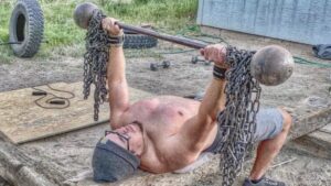 A person lifts a weight bar in a makeshift yard gym.