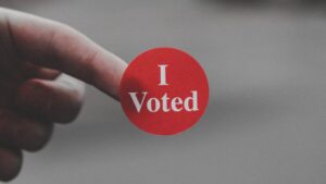 A finger with a sticker stuck to it reading "I Voted".