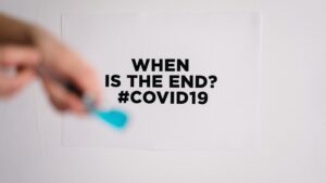 Hands in front of a piece of paper reading "WHEN IS THE END? #COVID19".