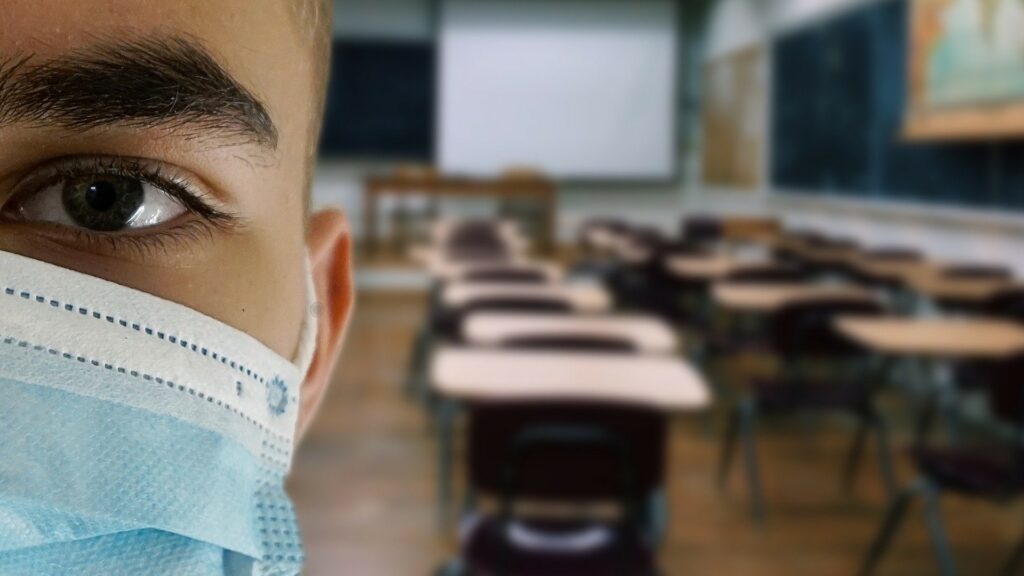 Composite of an empty classroom, with a person wearing a facemask facing camera in the front.