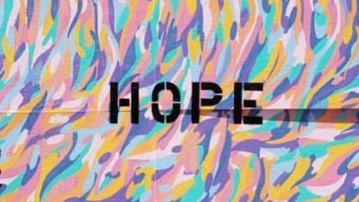 A painting with text reading "HOPE" in front of colorful wisps.