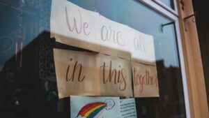 Signs on a storefront reading "We are all in this together".