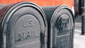 Two U.S. mailboxes standing next to each other on a city street.