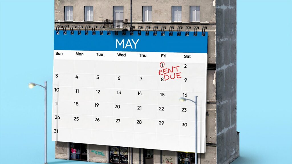 A calendar with the first day circled and labeled "RENT DUE", placed in front of an apartment building.